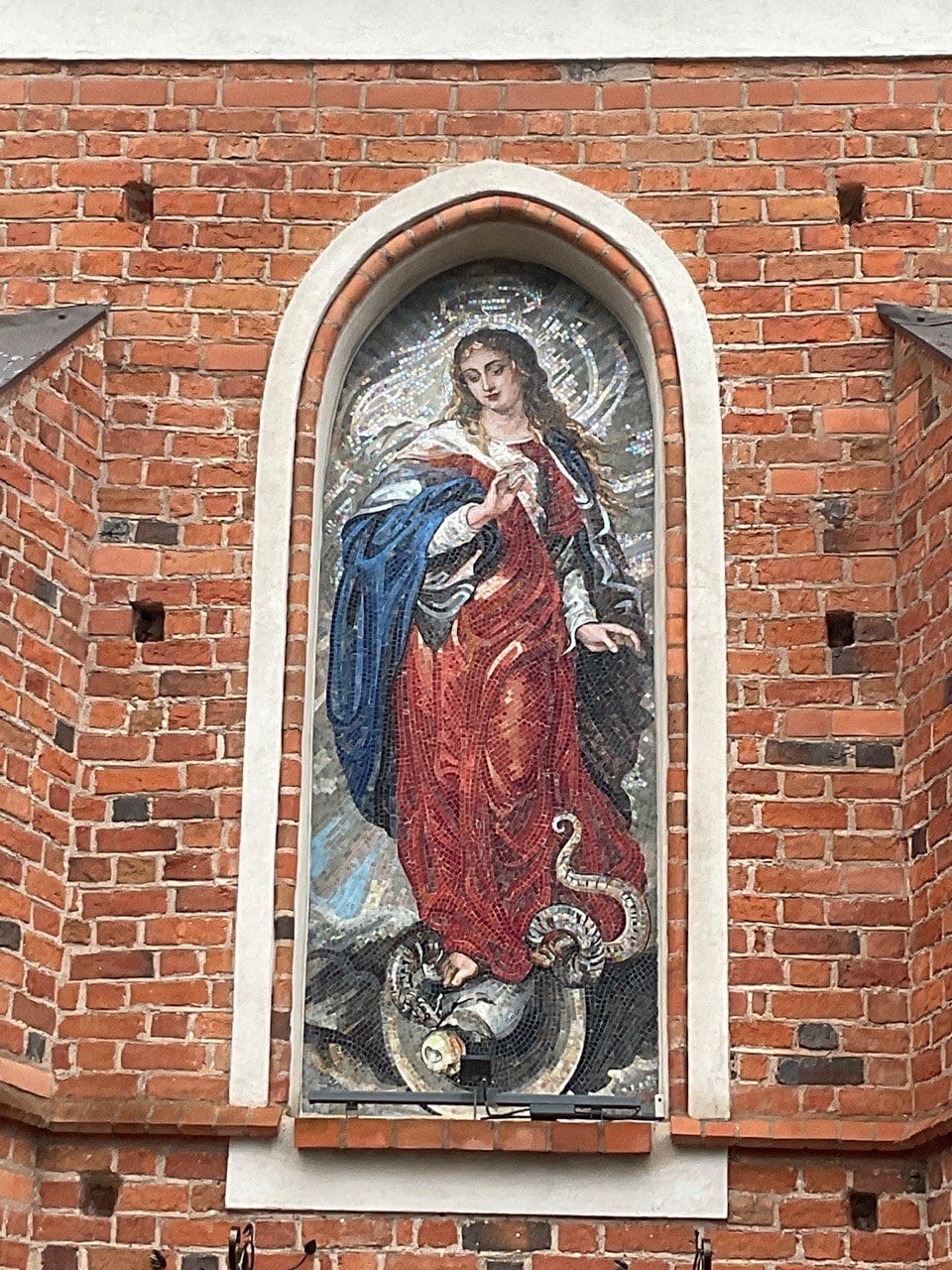 Neposkvrněná – mariánská mozaika v obloukovém výklenku na cihlové fasádě kostela